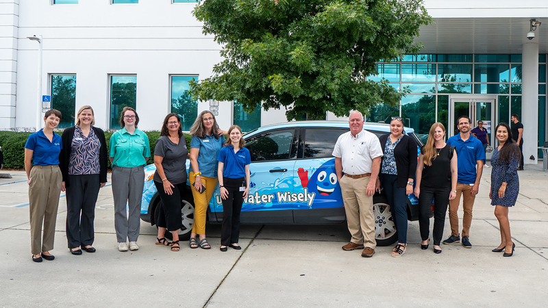 People standing infront of a car with a water conservation messagePeople standing infront of a house with vibrant groundcover
